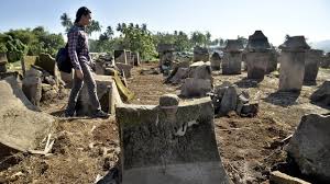 Seorang perempuan berjalan di antara batu megalitikum peninggalan nenek moyang di lahan terbuka, menggambarkan kepercayaan animisme dan dinamisme masyarakat Nusantara sebelum Islam.